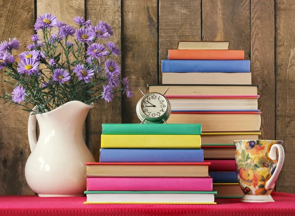 Bodegón con libros, un despertador y un ramo . — Foto de Stock