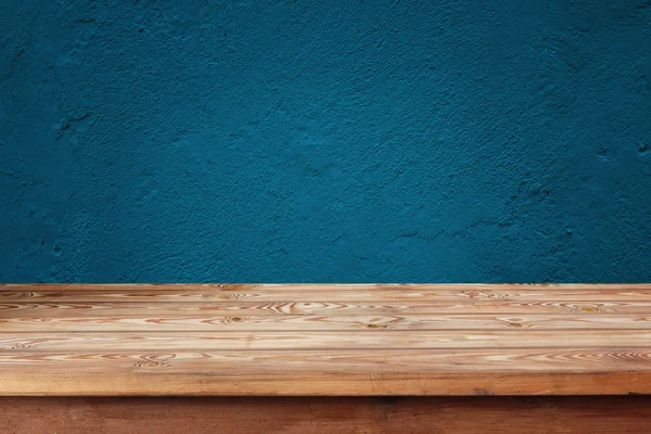 Empty wooden table against a blue wall — Stock Photo, Image