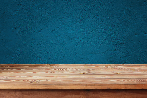 Empty wooden table against a blue wall