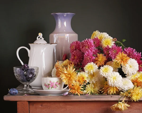 Still life with chrysanten en pruimen op een houten tafel op een — Stockfoto