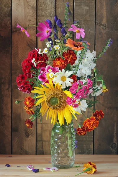 Still life with a bouquet to a glass bottle. — Stock Photo, Image