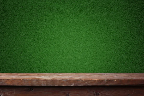 Mesa de madeira contra uma parede verde — Fotografia de Stock