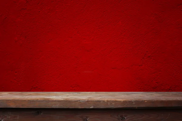 Holztisch vor roter Wand. — Stockfoto