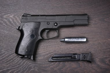 Black pneumatic pistol against a dark background. clipart