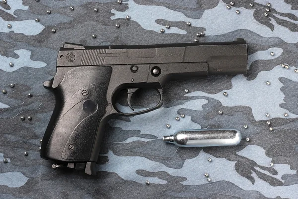 Pistola pneumatica nera su sfondo mimetico . — Foto Stock