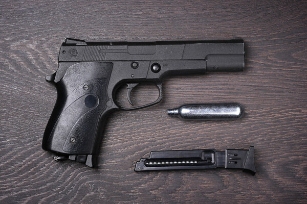 Black pneumatic pistol against a dark background.