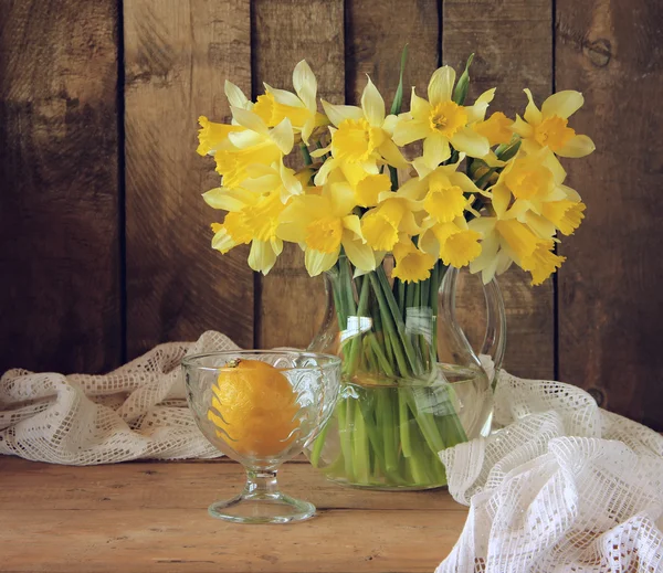 Stillleben mit gelben Narzissen und einer Zitrone. — Stockfoto