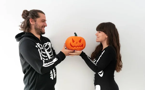 A couple of a boy and a girl dressed as skeletons holding a halloween pumpkin while they look into each other's eyes and smile — Stock Image Couple Boy Girl Dressed Skeletons Holding Halloween Pumpkin While Look Stock Photo