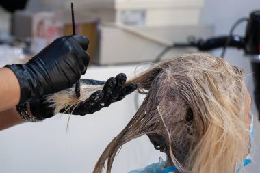 Kuaför müşterinin saçını boyuyor.