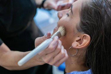 Genç bir kıza makyaj yapan bir kadın.