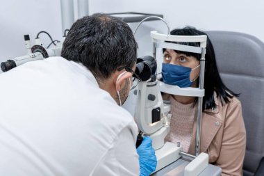 Bir kadının görme yeteneğini ölçen bir gözlükçü.