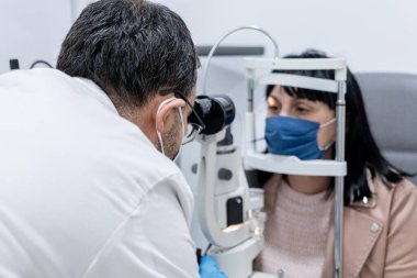 Bir kadının görme yeteneğini ölçen bir gözlükçü.