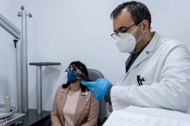 Bir kadının görme yeteneğini ölçen bir gözlükçü.