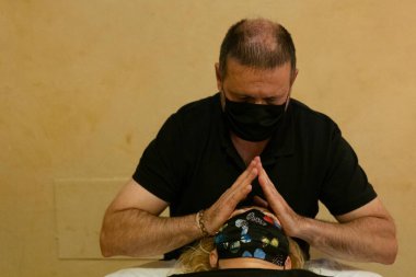 Masaj terapisti müşteriye yüz masajı yapıyor.