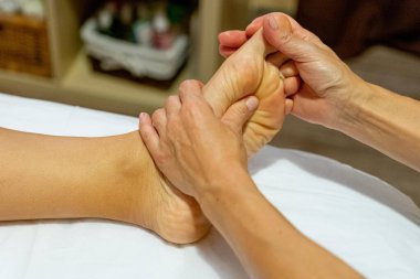 Masöz bir müşteriye ayak masajı yapıyor.