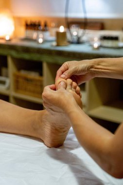 Masöz bir müşteriye ayak masajı yapıyor.