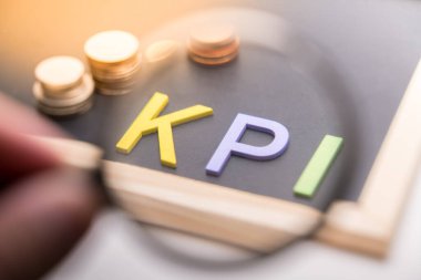 KPI yazı tahtasında ışık altında madeni parayla 