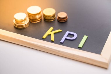 KPI yazı tahtasında ışık altında madeni parayla