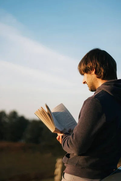 Молодий Чоловік Читає Книгу Сонячному Світлі Деревами Позаду Чистим Небом — стокове фото