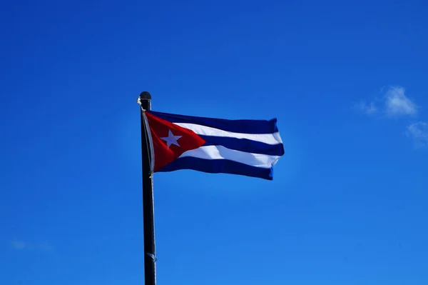   Küba bayrağı rüzgarla dalgalanıyor. Arkasında açık mavi bir gökyüzü                                   