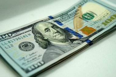 100 dolarlık banknotlardan oluşan bir destenin sol tarafını kapat. Beyaz ışıklandırmalı yumuşak bir kutunun içine alındı..