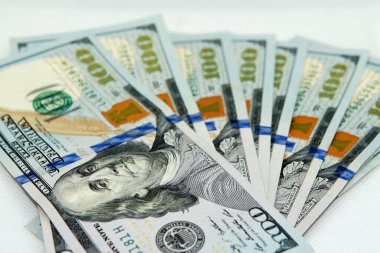 100 dolarlık banknotların yakın görüntüsü. Beyaz ışıklandırmalı yumuşak bir kutunun içine alındı.