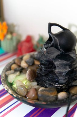Zen Su Dökümcüsünün yakın görüntüsü ve arka planda birkaç renkli süs eşyası.