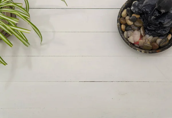 Düz bir şekilde, köşesinde yeşil bir bitki ve zen suyu çeşmesi olan beyaz ahşap bir masa görünüyordu.