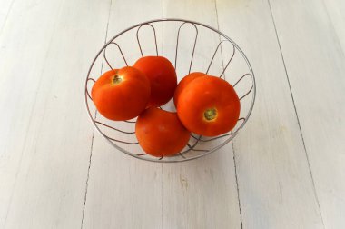 Beyaz bir masanın üstündeki kasenin içinde domatesler.