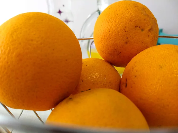 Close view of oranges in a bowl. On top of a white wood table