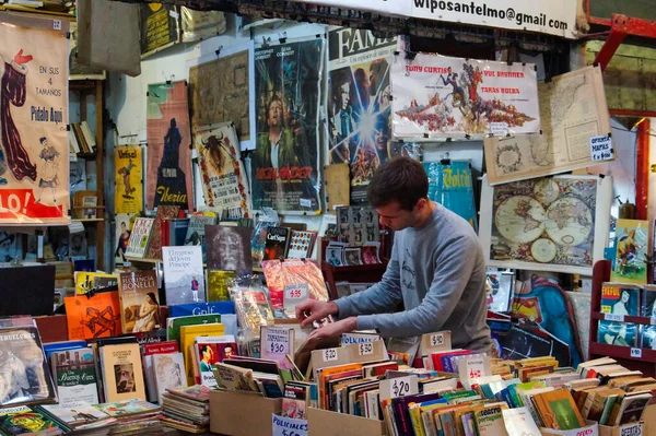 在阿根廷布宜诺斯艾利斯市San Telmo市场的旧书店里找一本书的年轻人 — 图库照片
