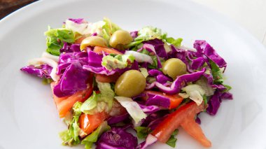 Beyaz bir masanın üstüne yerleştirilmiş taze Akdeniz usulü salataya yakından bakın.