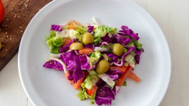 Akdeniz usulü taze bir salata bembeyaz bir masanın üstüne serilmiş.