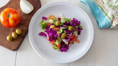 Akdeniz usulü taze bir salata bembeyaz bir masanın üstüne serilmiş.