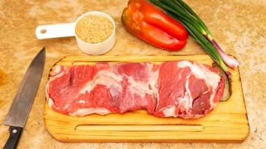 Kırmızı bir masanın üzerinde büyük bir parça çiğ kırmızı et yatıyordu. Etrafında başka maddeler ve akrabalar var..