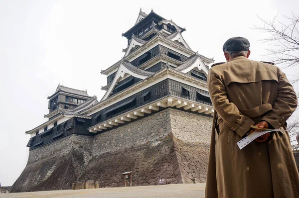 Siperdeki yaşlı Asyalı bir adam bir Japon kalesine bakıyor. 