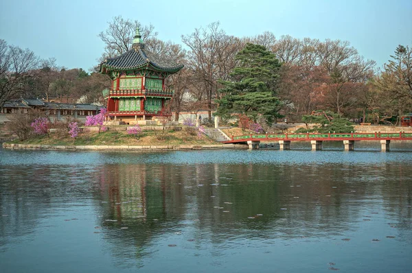 Gyeongbokgung Sarayı. Gölün kenarındaki parktaki köprüde renkli bina.