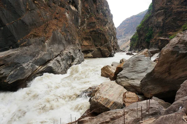 Çin dağlarındaki dağ nehri. Büyük kahverengi gri kaya oluşumu.