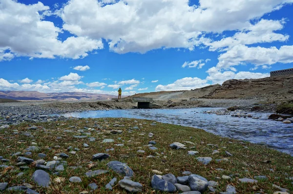 Güzel vadide gölün kenarında duran bir turist. Ön taraftaki çimlerde taşlar