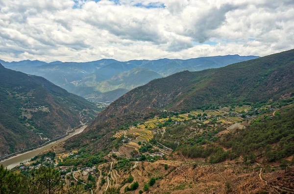 Çin dağlarındaki pirinç tarlalarının manzarası. Bulutlu gökyüzünün altındaki büyük dağlar