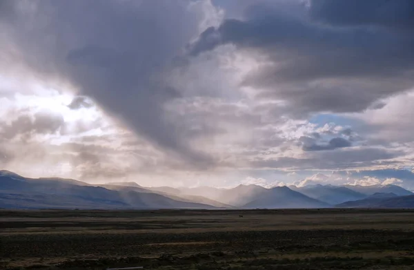 Yağmurlu bulutların arasından gün batımı. Tepelerin üzerinde dev kümülüs bulutları