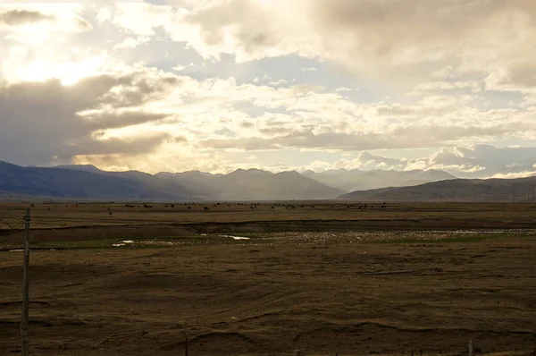 Günbatımı kümülüs bulutlarının ardında kahverengi bozkırların üzerinde.