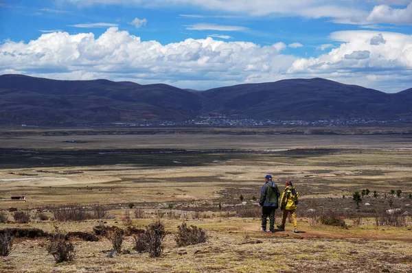Vadi manzarasına bakan iki kişi. Arka planda kümülüs bulutları olan mavi gökyüzü