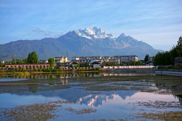 Kasabanın dağ evi manzarası. Alacakaranlıkta büyük dağ. Akşamın erken saatlerinde göl kenarında