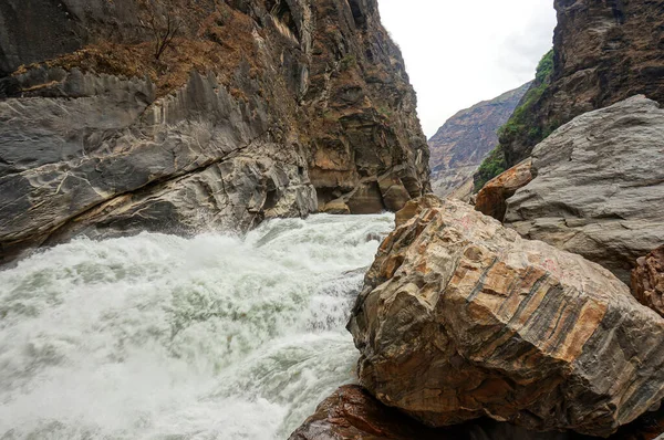 Kahverengi dağlardaki vahşi nehir. Önde çizgili kaya