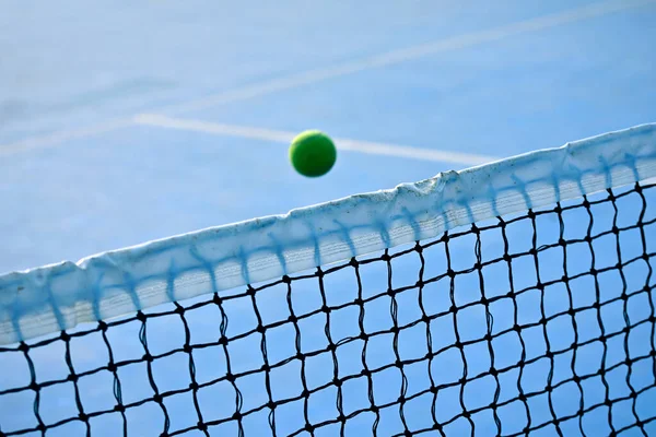 Tennis ball over net on tennis court background. Close-up Tennis ball hitting to net.