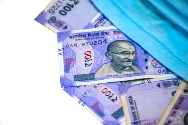 Hindistan 100 rupisi ve yüz maskesi beyaz arka planda izole edilmiş.