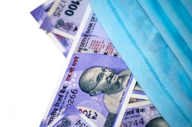 Hindistan 100 rupisi ve yüz maskesi beyaz arka planda izole edilmiş.