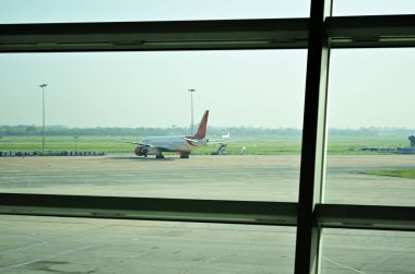 Delhi, Hindistan - 07 Eylül 2015: Air India 'nın havaalanı pistindeki uçağı. Havaalanı lobisinden pencereye doğru çekiliyor..