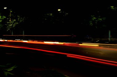 Karanlık bir gecede, Araba Işığı şehir caddesinde yol alır. Fotoğraf uzun pozla çekilir..